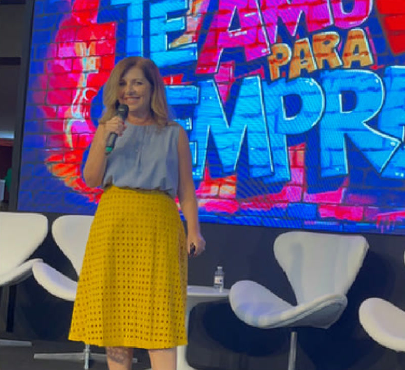 Claudia Fernandes no palco, diante do telão Te Amo Para Sempre