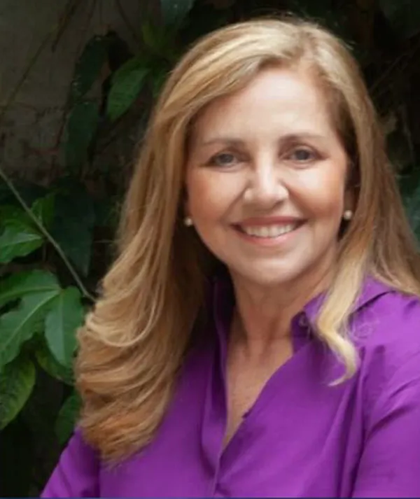 Claudia Fernandes sorrindo, de camisa roxa